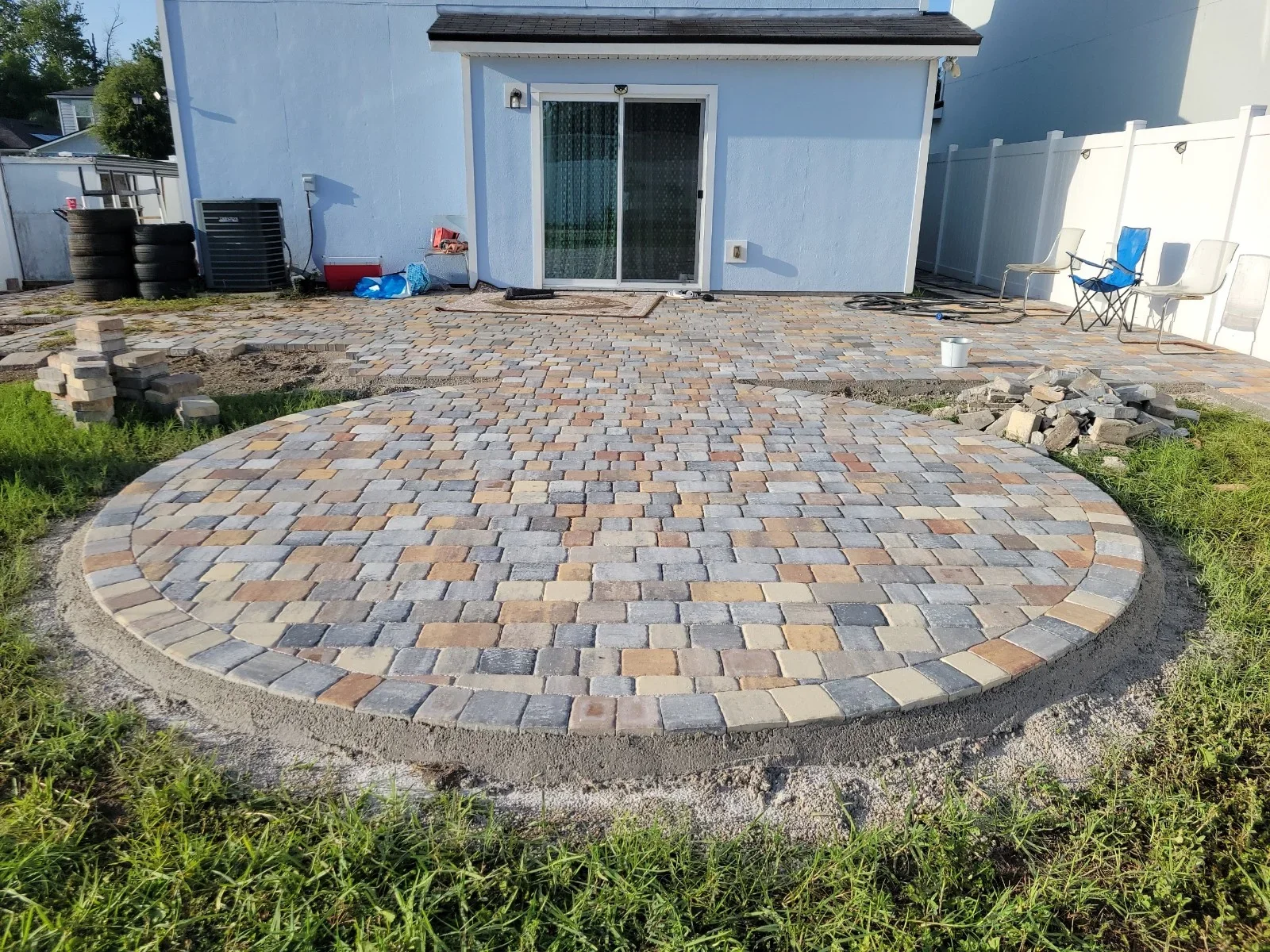 Circular paver patio with multi-colored concrete pavers in radiating pattern and stone edging