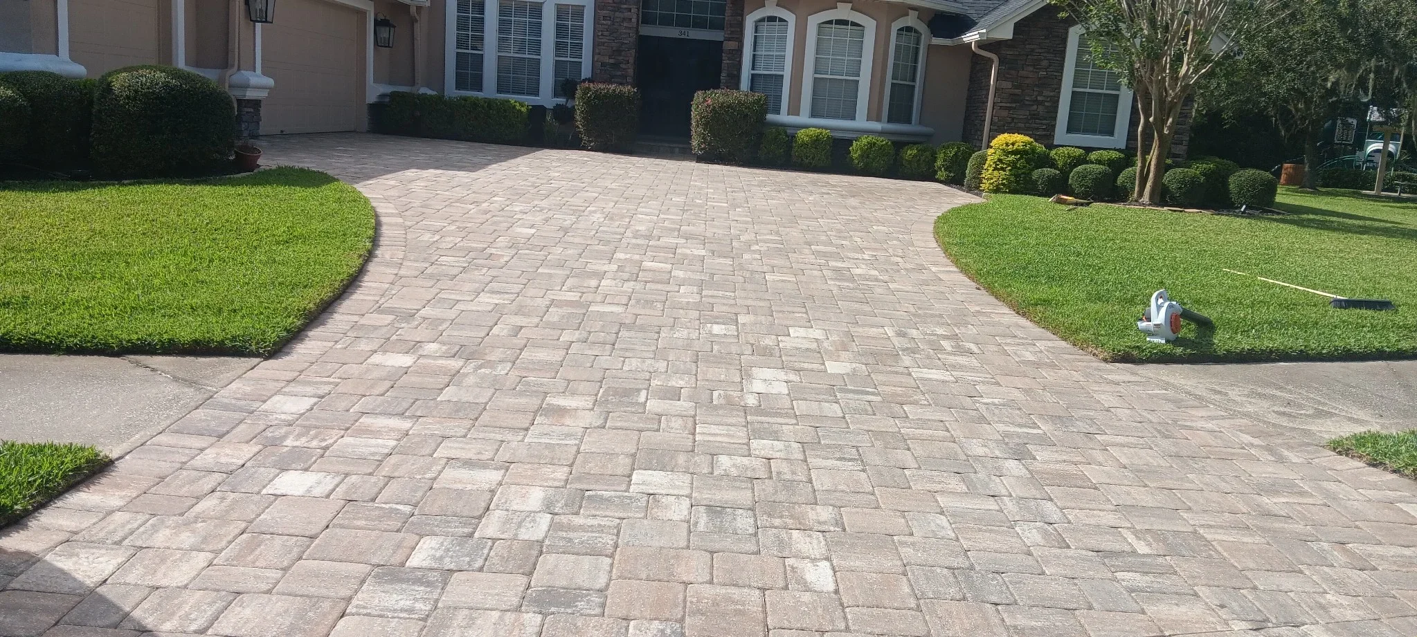 Curved concrete paver driveway with herringbone pattern and manicured lawn borders