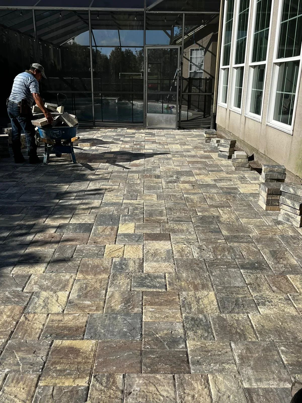 Tumbled stone paver patio installation with running bond pattern and base preparation work in progress