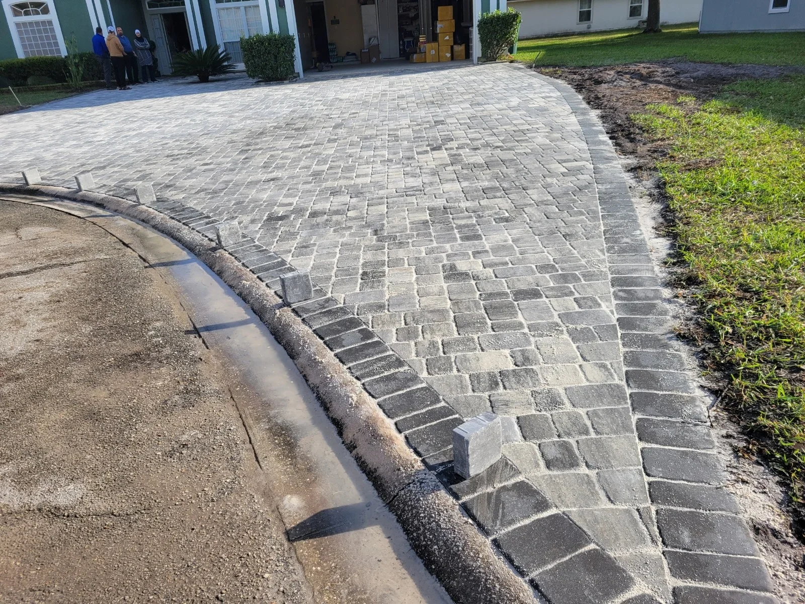 Gray and tan permeable pavers installed in running bond pattern with concrete edge restraint and drainage