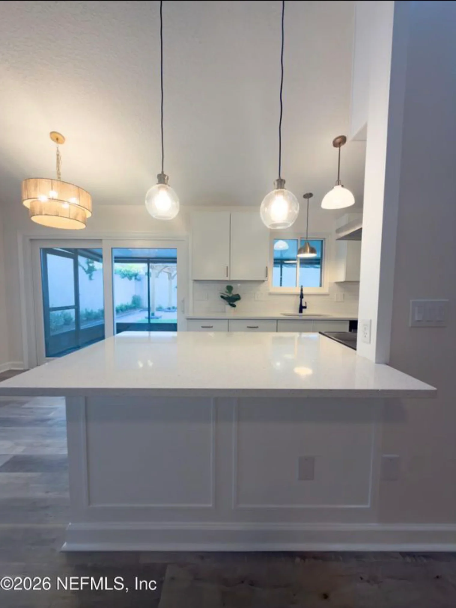 Modern kitchen with white cabinets, quartz counters, island, and pendant lighting fixtures