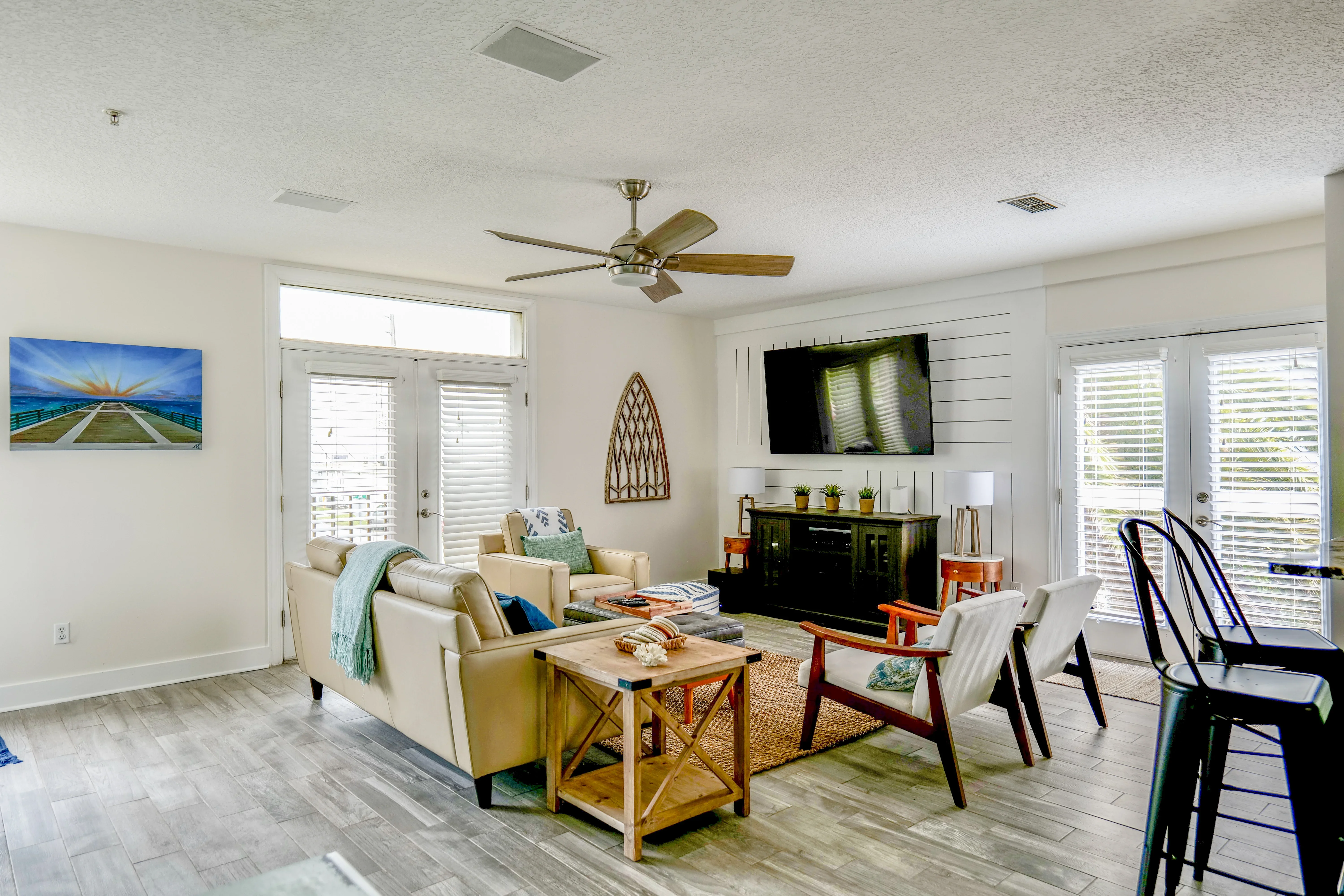 Open concept living room with recessed lighting, ceiling fan, shiplap accent wall, and plantation shutters