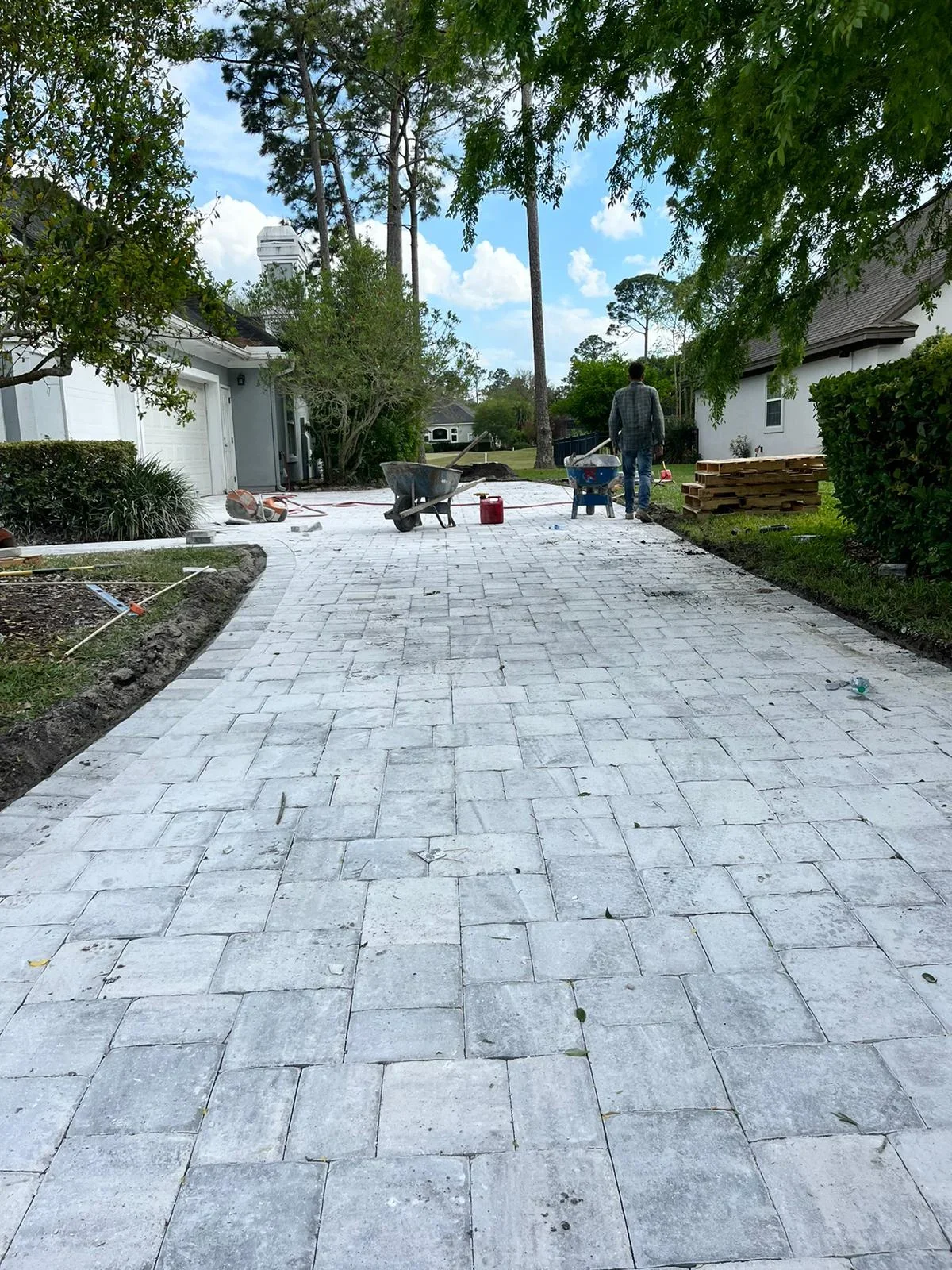 Concrete paver patio in herringbone pattern during installation between two white homes