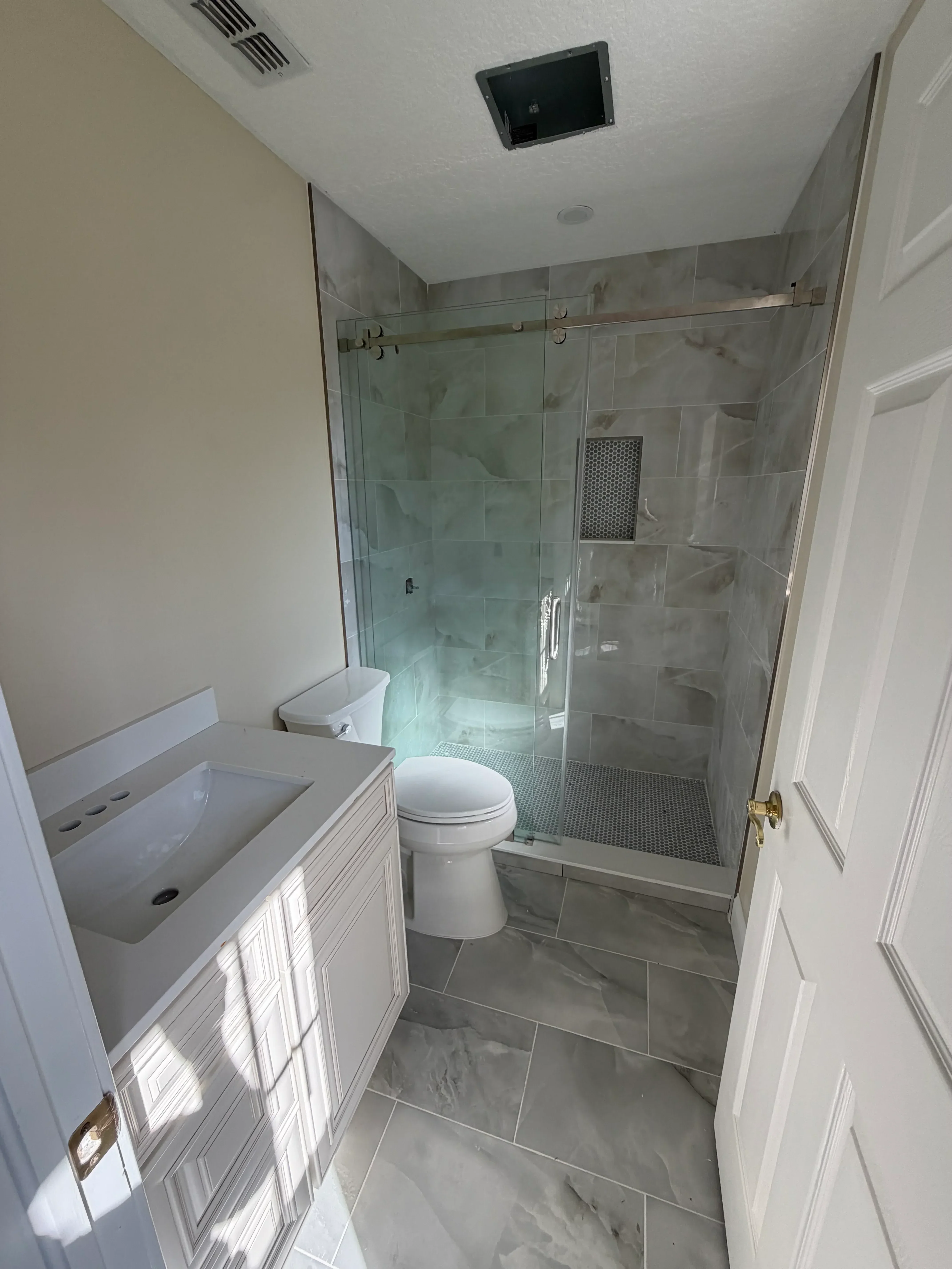 Marble tile bathroom with frameless glass shower enclosure and coffered ceiling