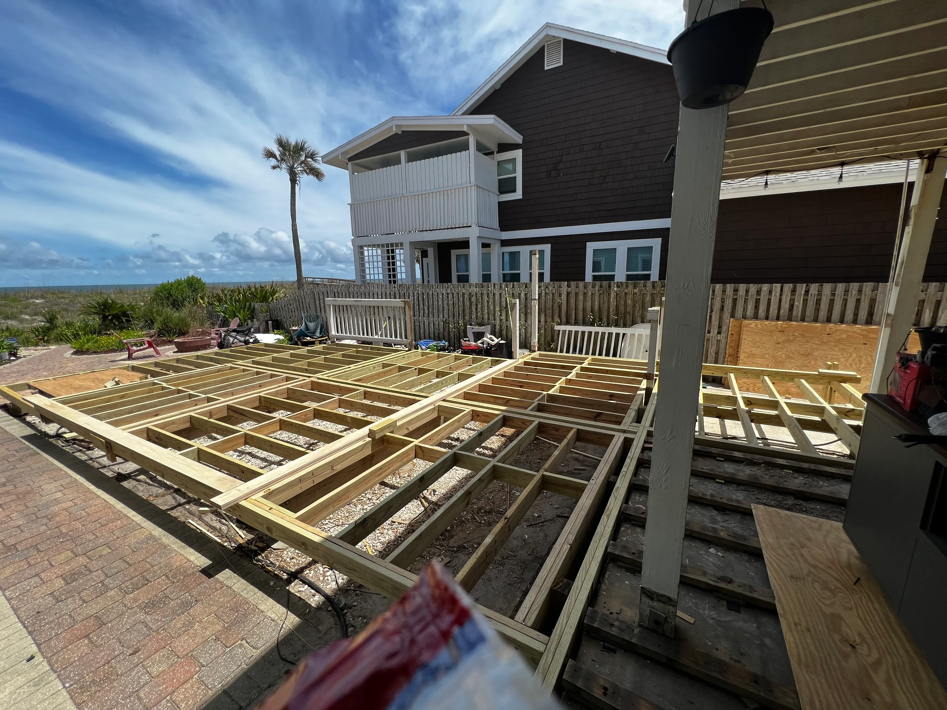 Elevated deck framing with pressure-treated lumber joists and beams during construction phase