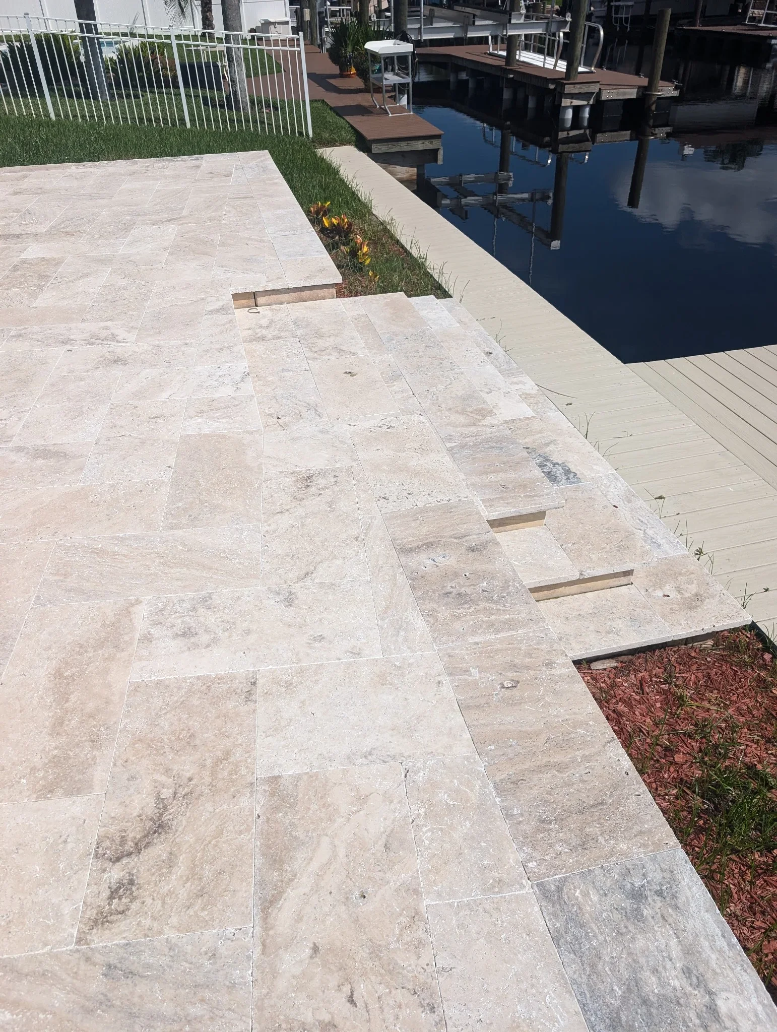 Light stone herringbone patio with planter beds and metal railings overlooking waterfront