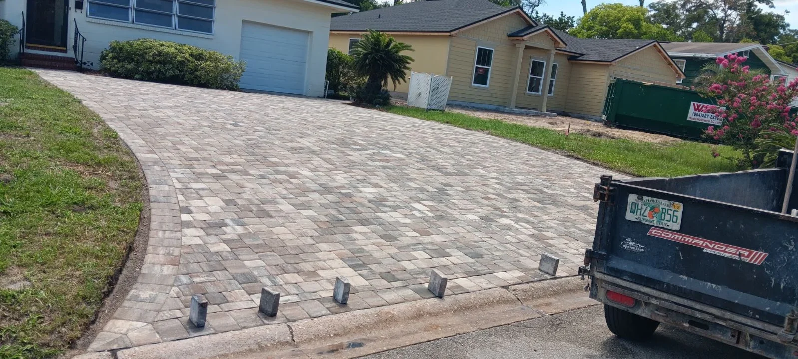 Multi-tone gray and tan permeable paver driveway with edge restraints and finished landscaping borders