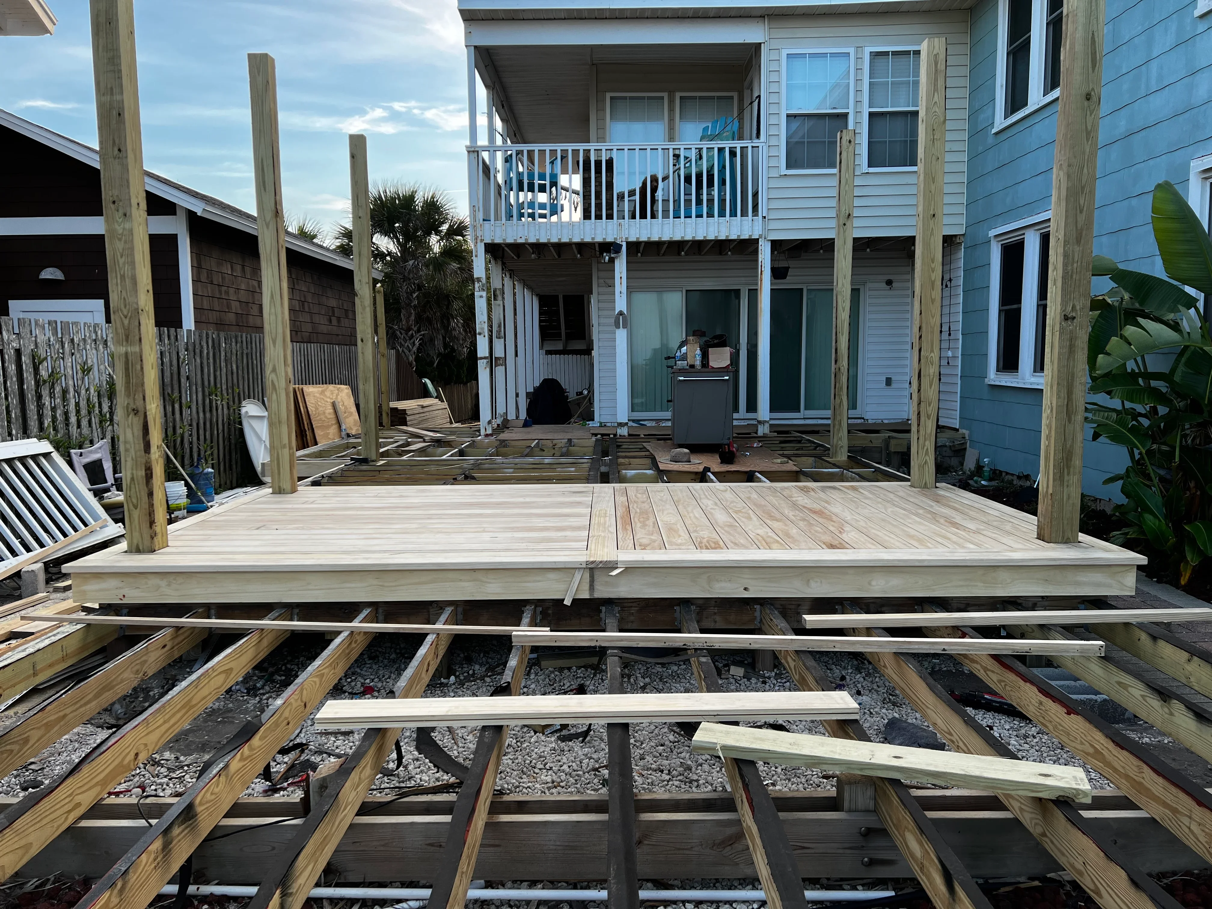 Elevated deck framing with pressure-treated posts, joists, and composite decking during construction phase