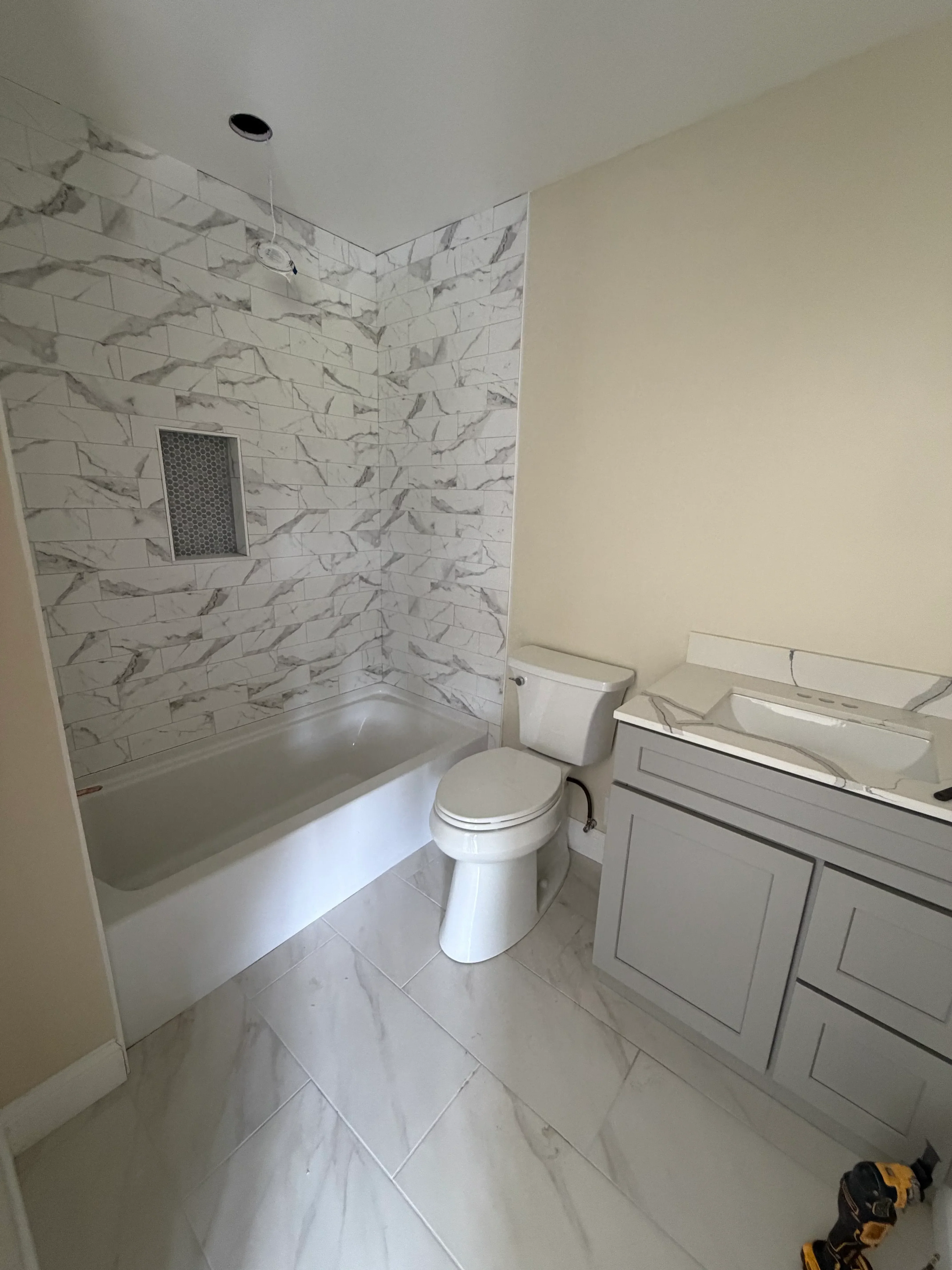 Bathroom with marble-look tile flooring, white subway tile walls, and updated fixtures