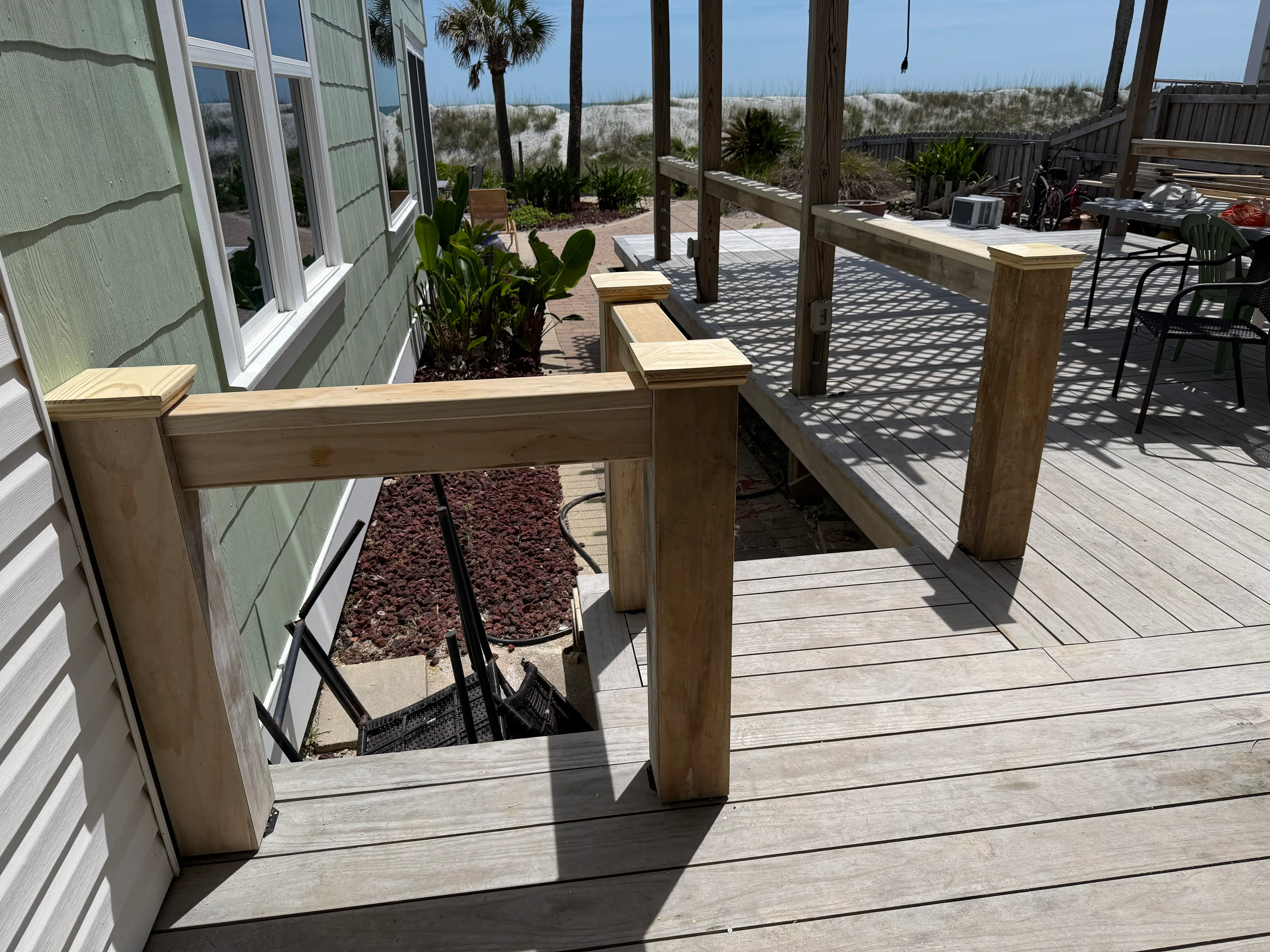 Wooden deck with custom railings, posts, and integrated planters overlooking dunes