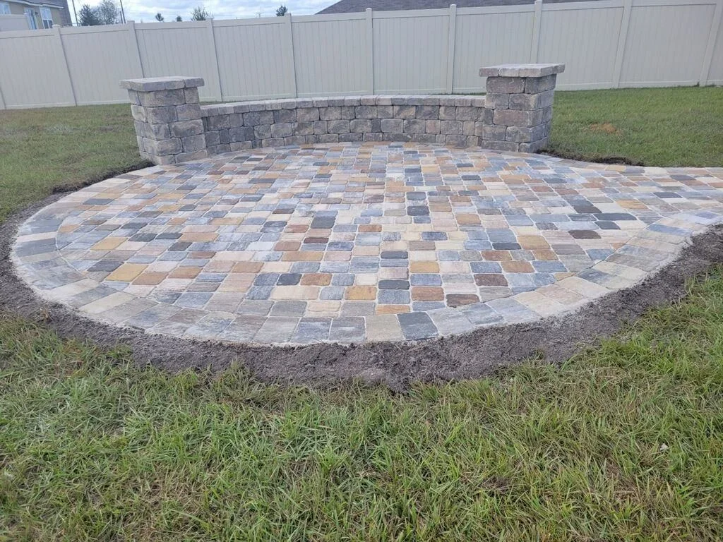 Curved paver patio with multi-colored diamond pattern and stone retaining wall with cap